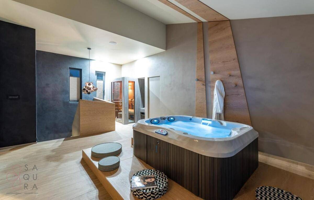 Geräumiger Wellnessbereich mit Whirlpool und integrierter Sauna für luxuriöse Entspannung.