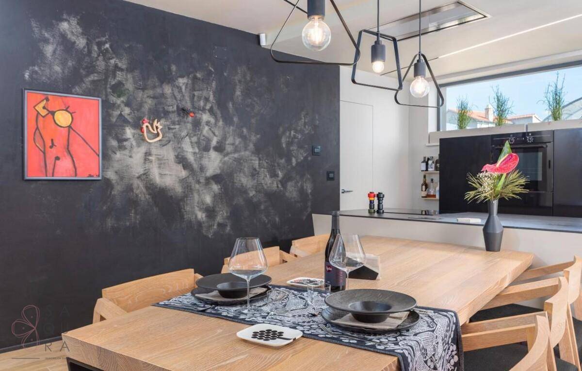Moderner Essbereich mit Holztisch, schwarzen Stühlen und künstlerischer Wandgestaltung.