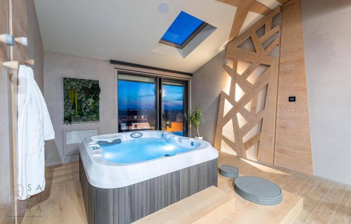 Modernes Interieur mit Whirlpool, großem Fenster und Dachfenster für viel Tageslicht.