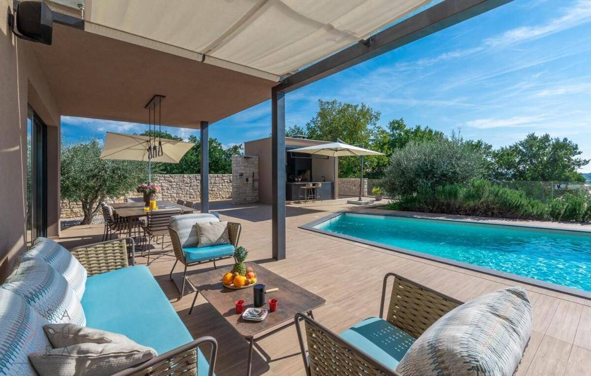 Gemütliche überdachte Terrasse mit Lounge-Möbeln und Blick auf den Pool und die Landschaft.