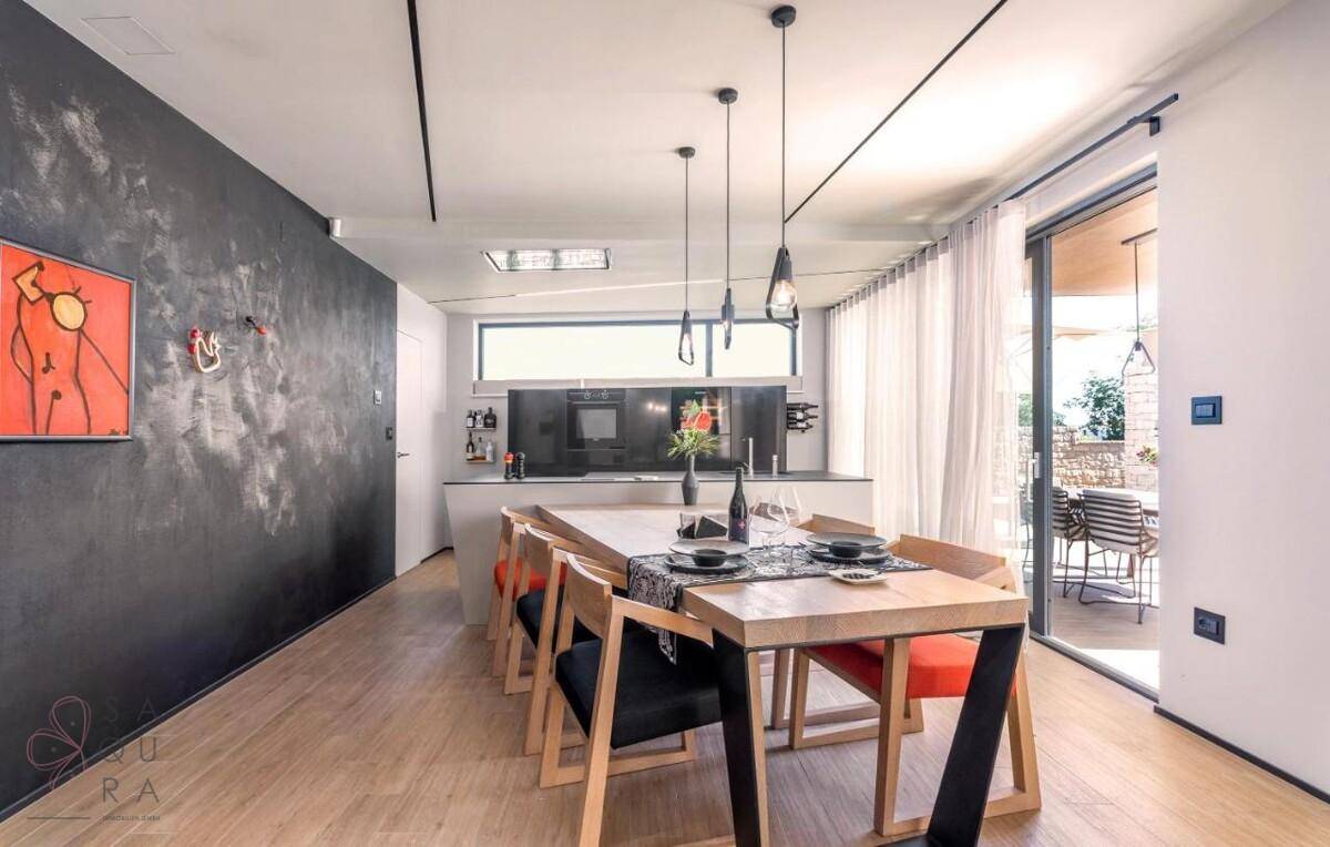 Moderner Essbereich mit Holztisch, schwarzen Stühlen und Zugang zur Außenterrasse.