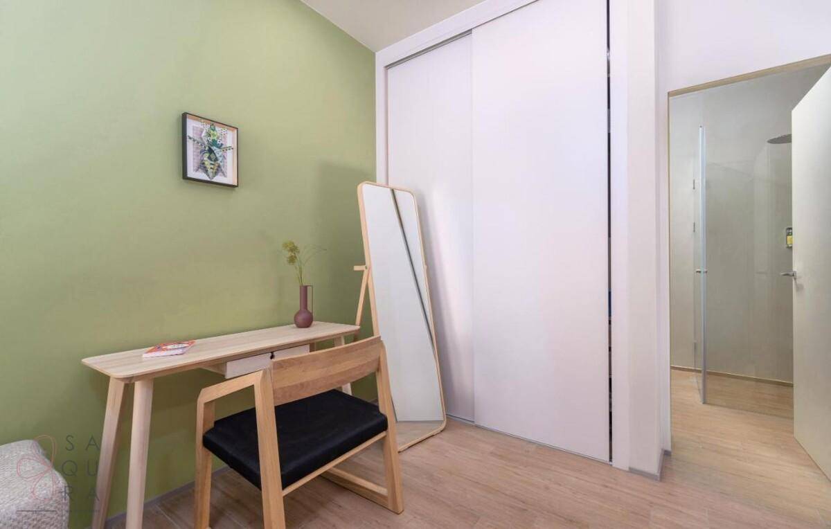 Helles Zimmer mit Schreibtisch, Stuhl und integriertem Kleiderschrank, ideal als Arbeitsbereich.