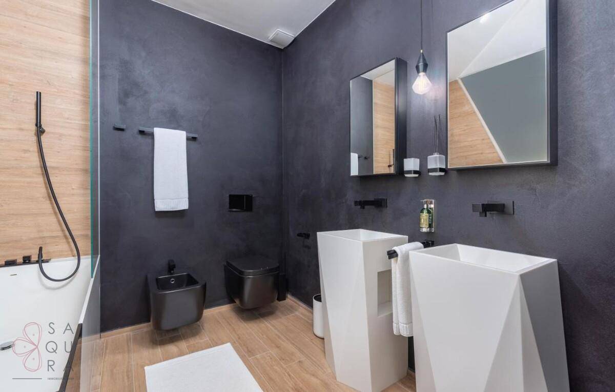 Elegantes Badezimmer mit zwei modernen Waschbecken, Bidet und dunklen Wänden.