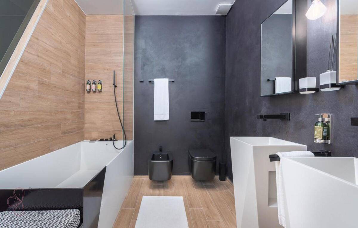 Stilvolles Badezimmer mit moderner Badewanne, Doppelwaschbecken und dunklen Wänden.