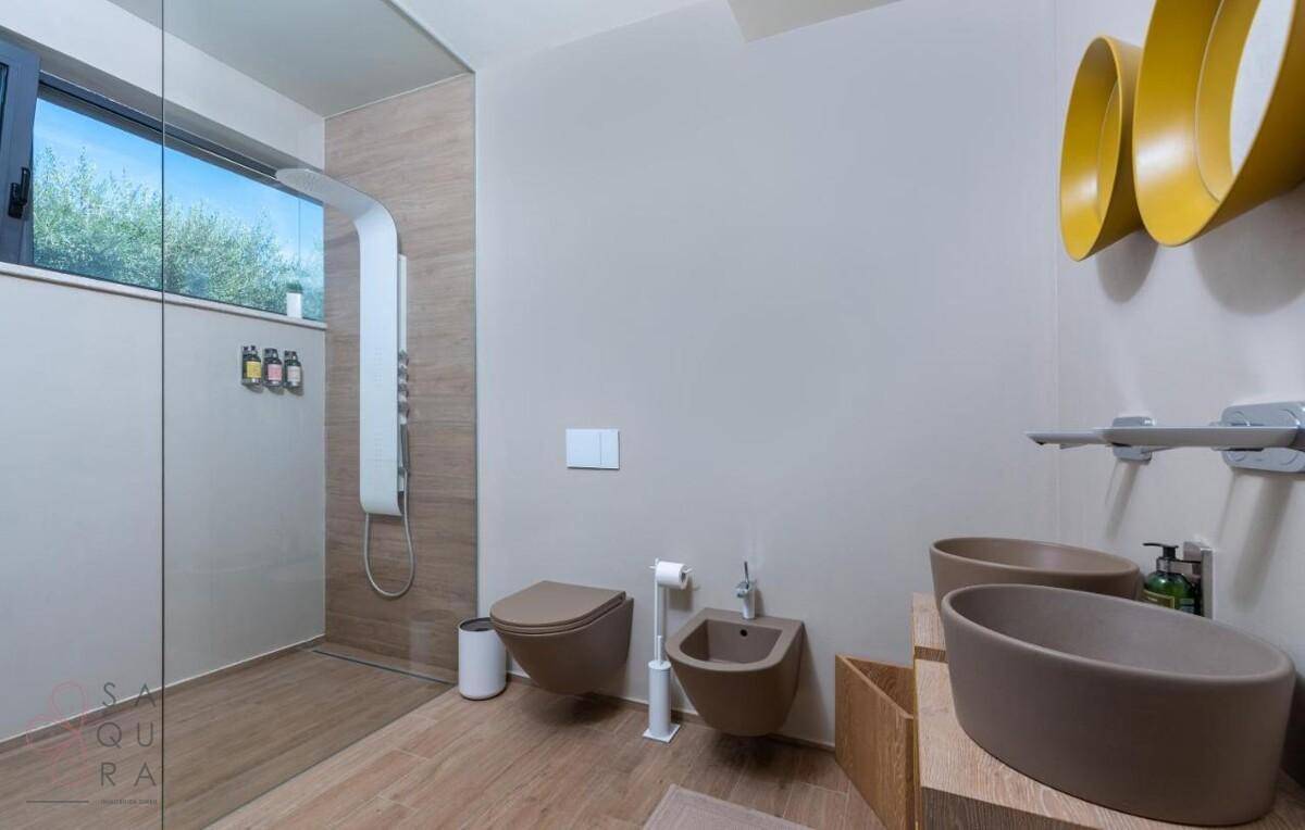 Helles Badezimmer mit großer begehbarer Dusche, Doppelwaschbecken und Fenster.