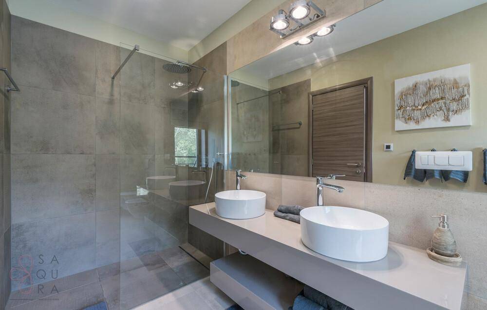 Elegantes Badezimmer mit Doppelwaschbecken, großem Spiegel und geräumiger begehbarer Dusche.