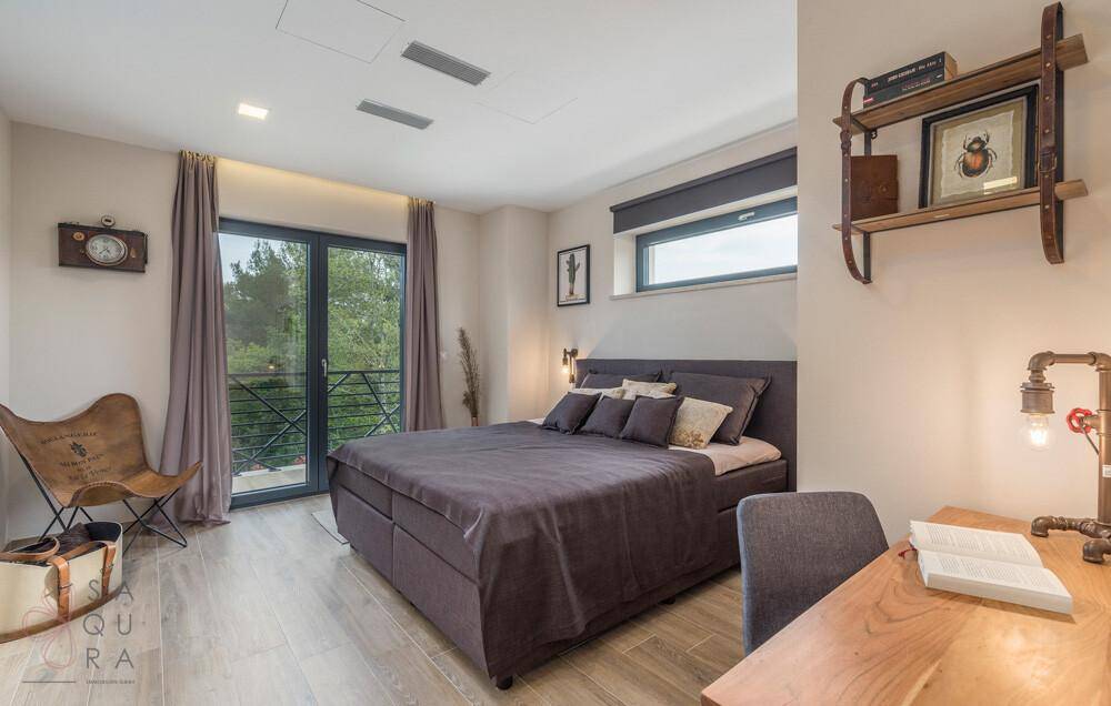 Gemütliches Schlafzimmer mit Doppelbett, Holzboden und Zugang zu einem Balkon mit Waldblick.