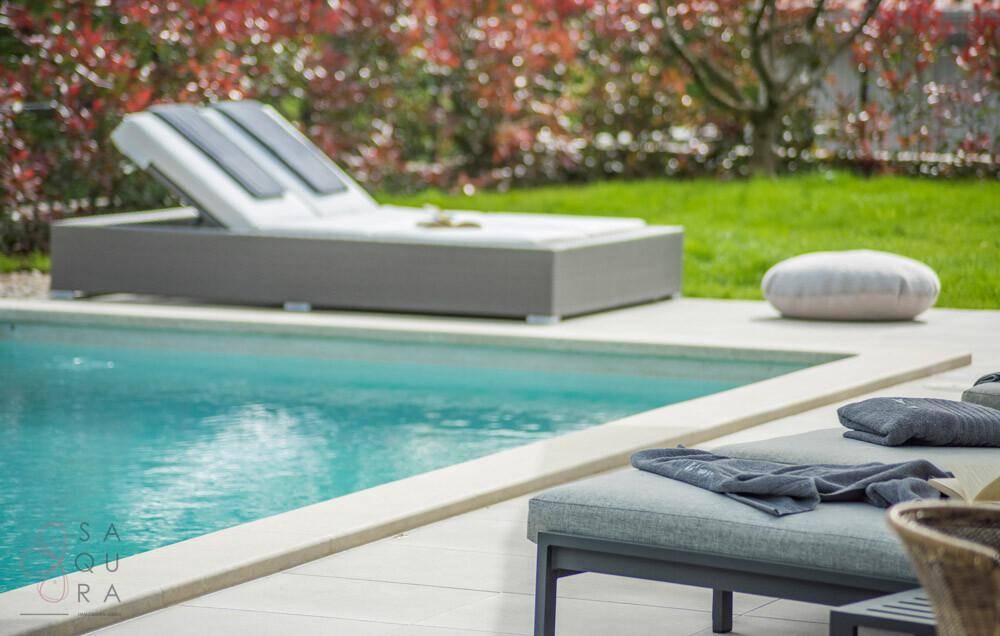 Nahaufnahme des Poolbereichs mit eleganten Sonnenliegen und einem bequemen Bodenkissen.