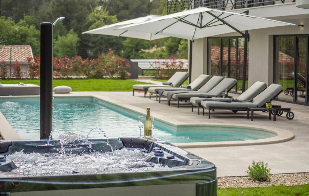 Entspannender Whirlpool mit Sektgläsern neben dem Pool und den Sonnenliegen.