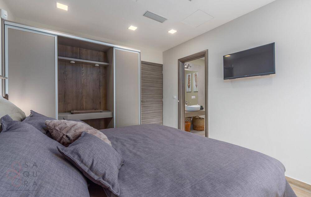 Schlafzimmer mit großem Bett, integriertem Kleiderschrank und direktem Zugang zum Badezimmer.