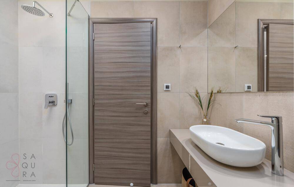 Modernes Badezimmer mit begehbarer Dusche, Einzelwaschbecken und stilvoller Holztür.