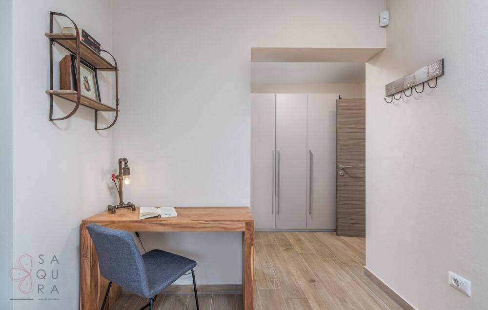 Kleiner Arbeitsbereich mit Holzschreibtisch, Regal und integrierten Schränken im Flur.
