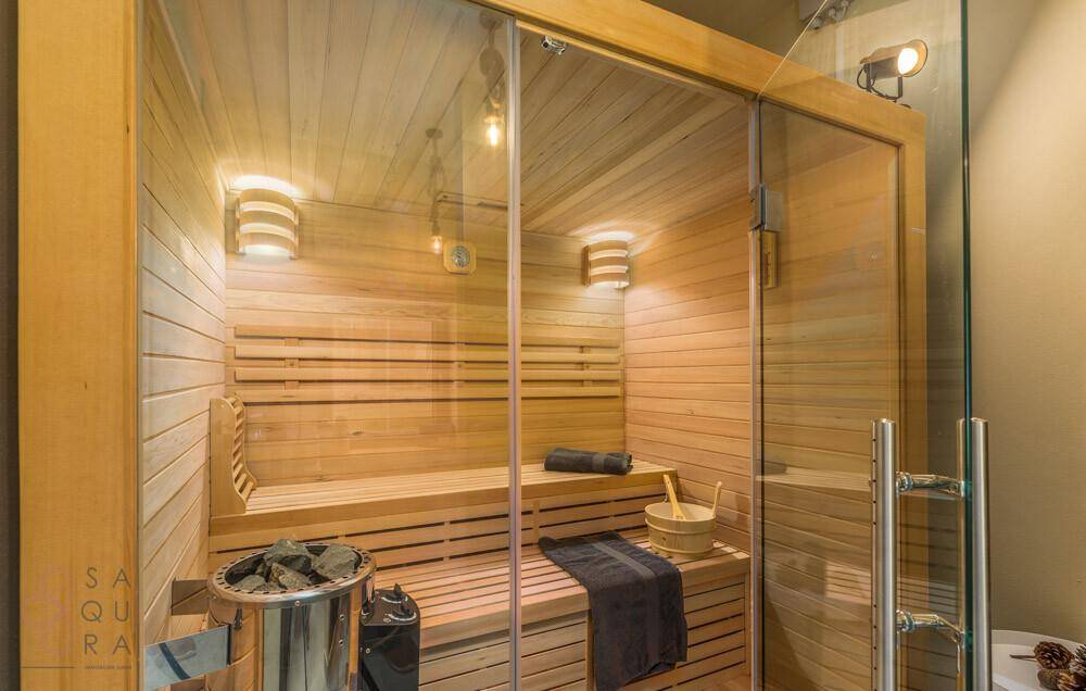 Private Sauna mit Holzverkleidung, Bänken und stimmungsvoller Beleuchtung für Entspannung.