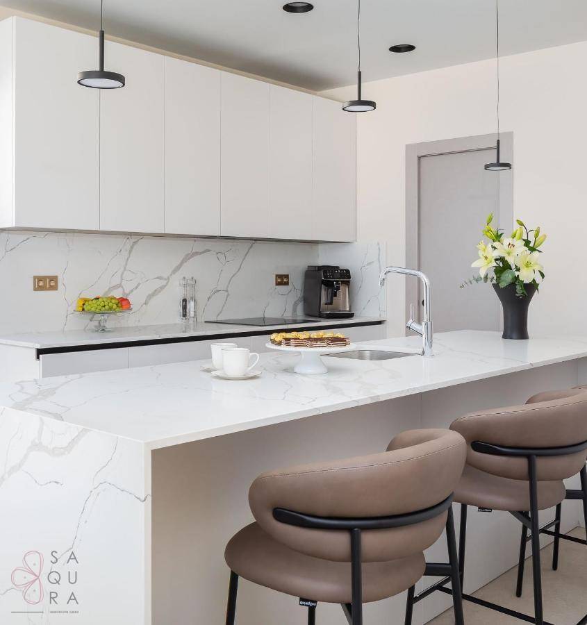 Moderne, helle Küche mit weißer Kücheninsel, Marmor-Arbeitsplatten und integrierten Geräten.