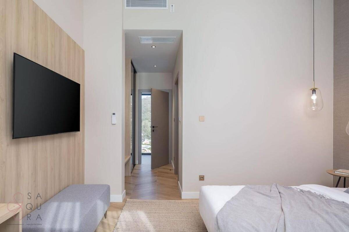 Helles Schlafzimmer mit Holzwandakzent und Blick in den Flur, der zu weiteren Räumen führt.
