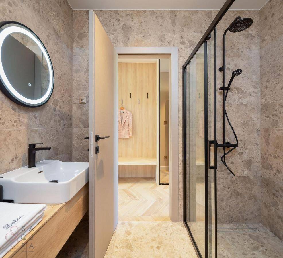 Modernes Badezimmer mit begehbarer Dusche, stilvollen Fliesen und beleuchtetem Spiegel.