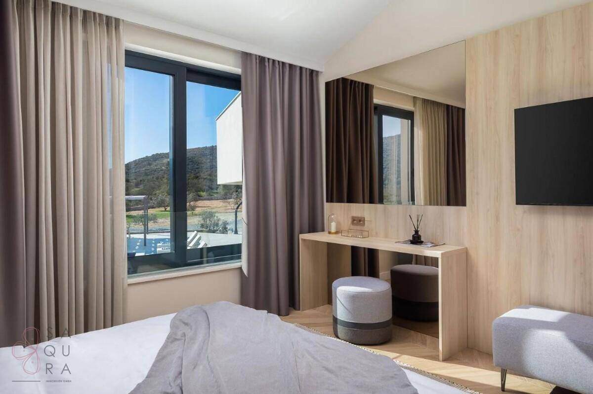 Helles Schlafzimmer mit großem Fenster, Schreibtisch und Blick auf die grüne Landschaft.