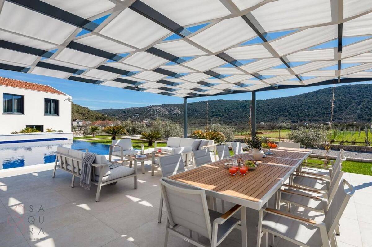 Großzügige Terrasse mit Ess- und Lounge-Bereich unter einer Pergola, ideal für Entspannung im Freien.