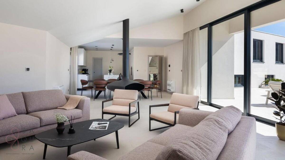 Geräumiges Wohnzimmer mit bequemen Sofas, modernem Hängekamin und großen Fenstern zur Terrasse.