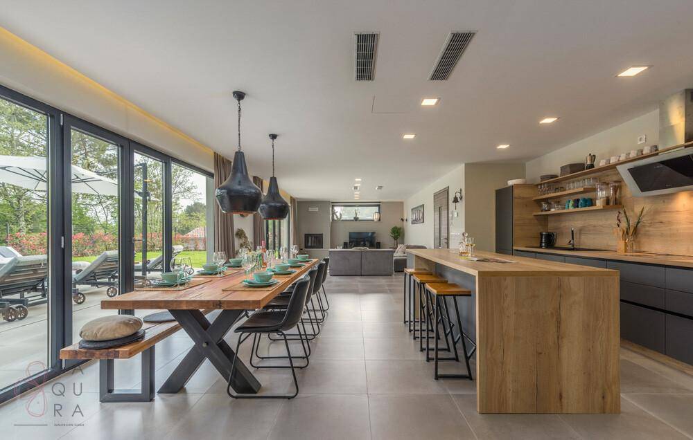 Offener Wohn-Essbereich mit großer Küche, Esstisch und Zugang zur Terrasse mit Pool.