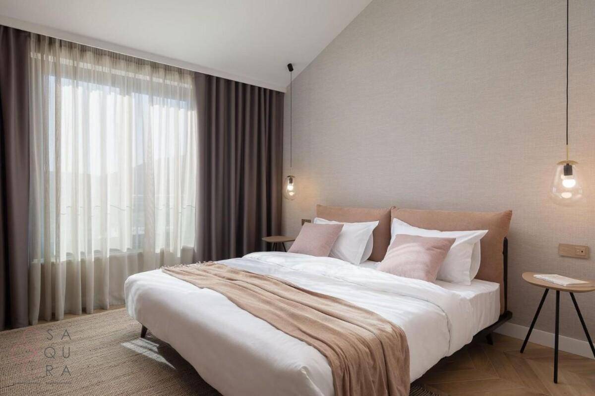 Gemütliches Schlafzimmer mit Doppelbett, großen Fenstern und Blick auf die grüne Landschaft.