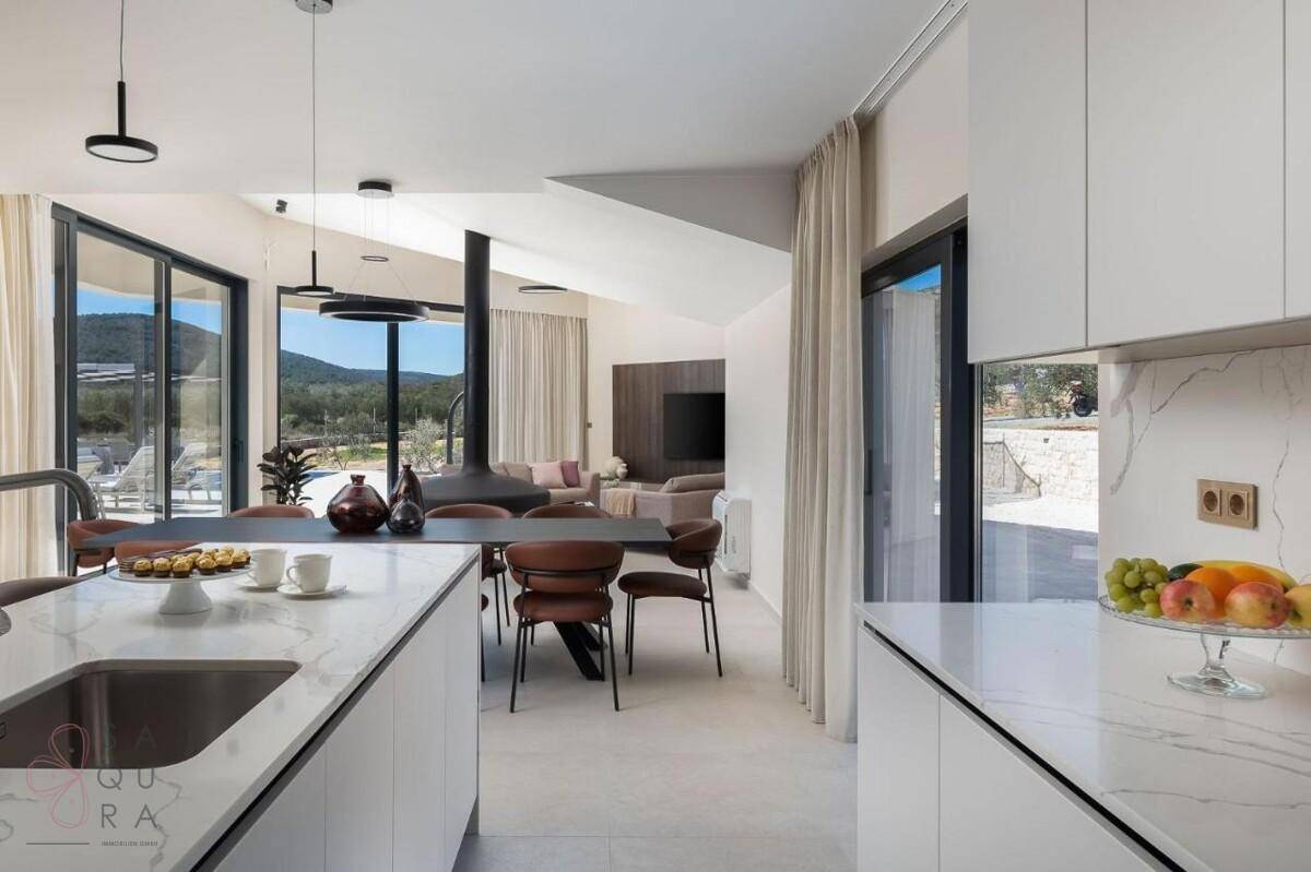 Offene Küche und Essbereich mit moderner Einrichtung, Kücheninsel und Blick ins Wohnzimmer.