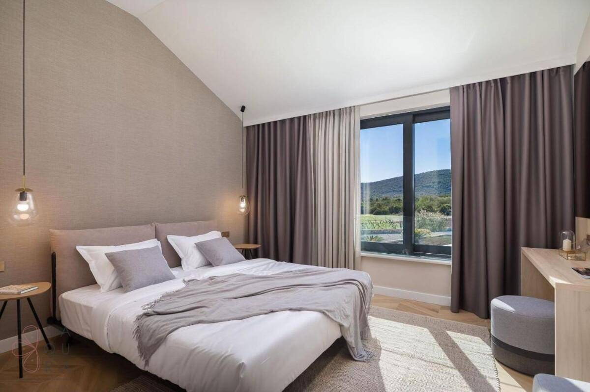 Komfortables Schlafzimmer mit Doppelbett, großen Fenstern und Blick auf die umliegende Natur.