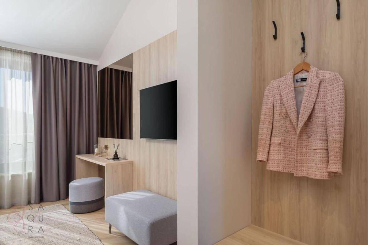 Helles Schlafzimmer mit Ankleidebereich, Holzwandakzent und großem Fenster.