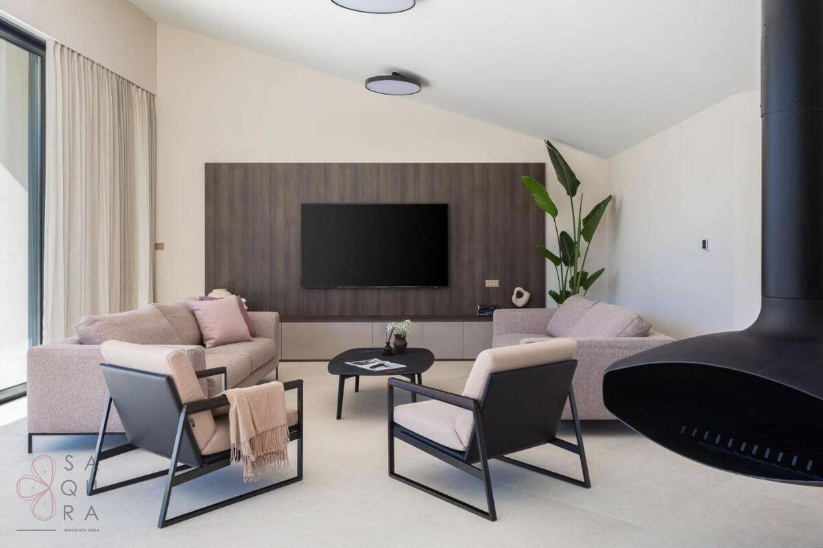 Modernes Wohnzimmer mit bequemen Sofas, Fernseher und Hängekamin, offen zum Essbereich.