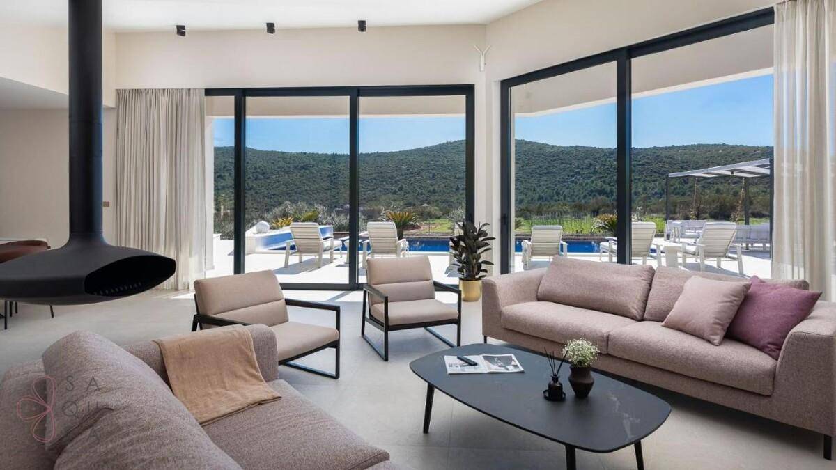 Helles Wohnzimmer mit großen Schiebetüren, die den Blick auf den Pool und die Landschaft freigeben.