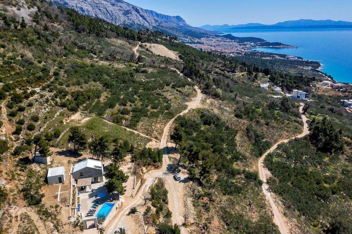 Weitläufige Luftaufnahme der Immobilie mit Pool, umgeben von grüner Landschaft und Meerblick.