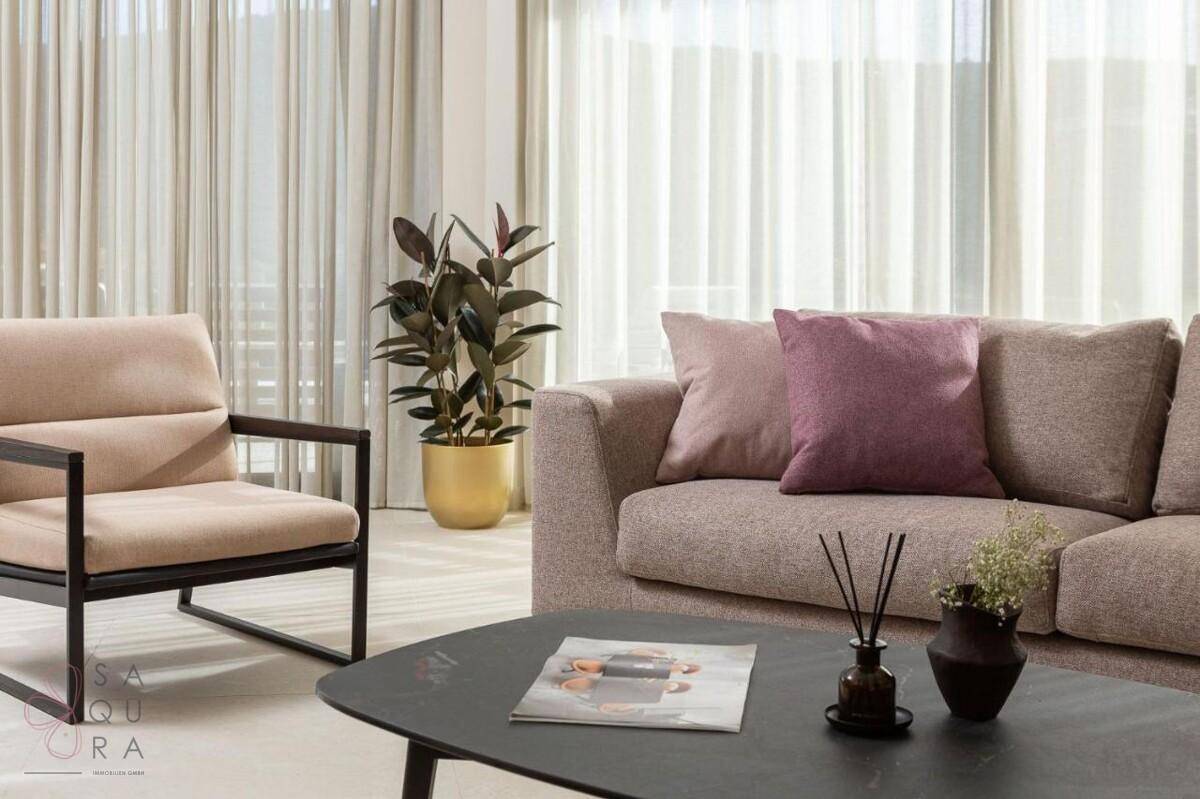 Detailansicht des Wohnzimmers mit bequemen Sofas, Kissen und einer Zimmerpflanze.