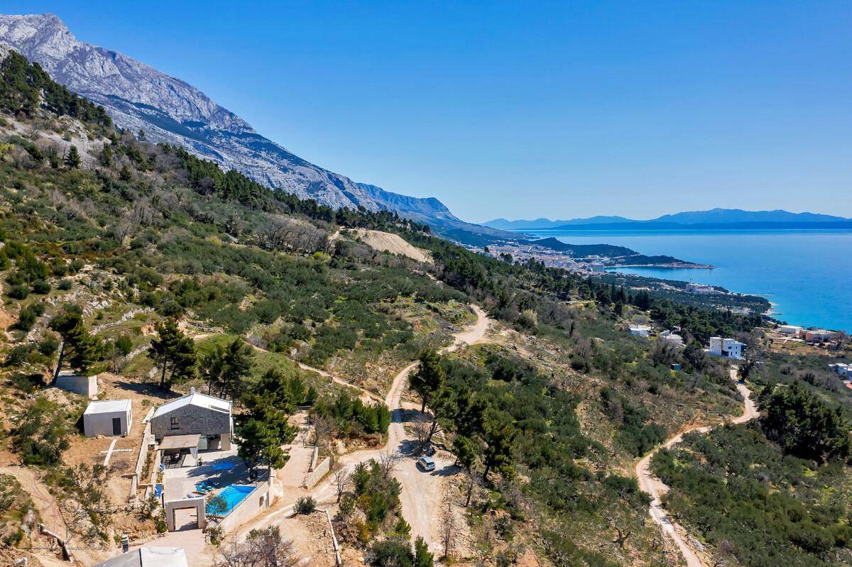 Weitläufige Luftaufnahme der Immobilie mit Pool, umgeben von grüner Landschaft und Meerblick.