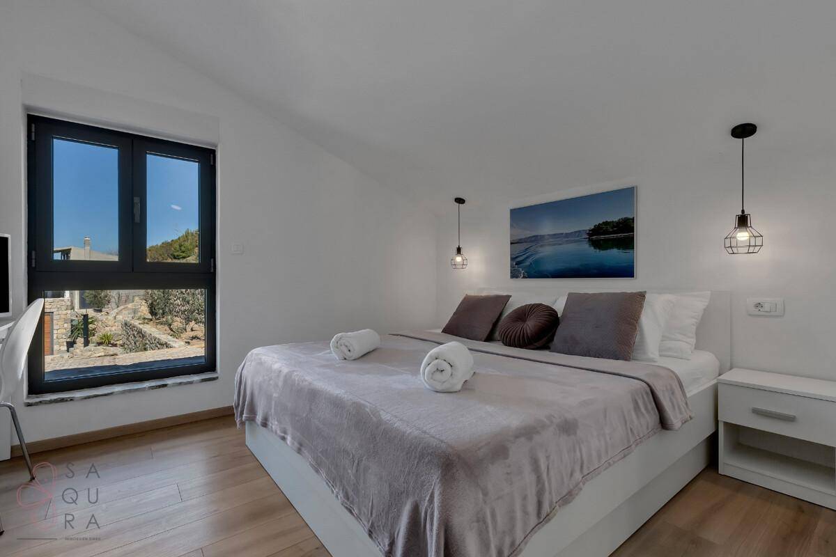 Helles Schlafzimmer mit Doppelbett, Holzboden und großem Fenster mit Blick ins Grüne.