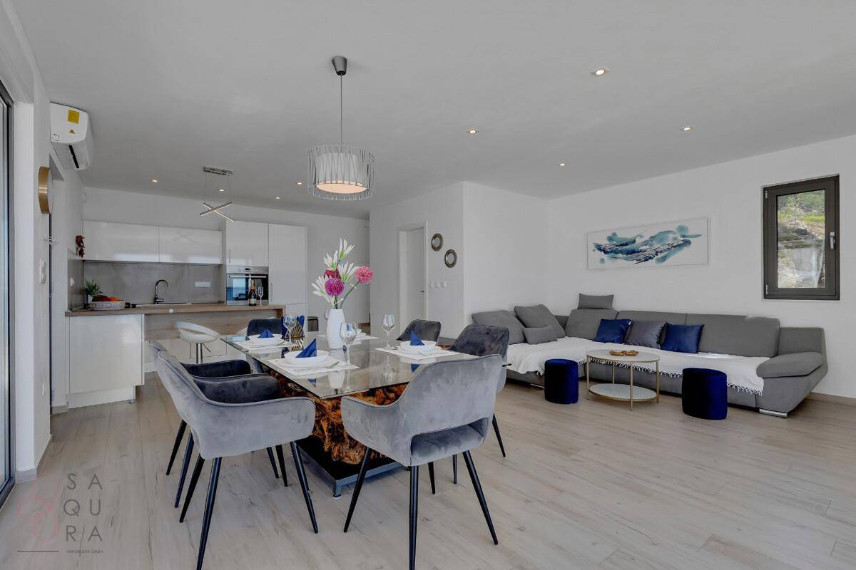 Offener Wohn-, Ess- und Küchenbereich mit modernen Möbeln und Zugang zur Terrasse.