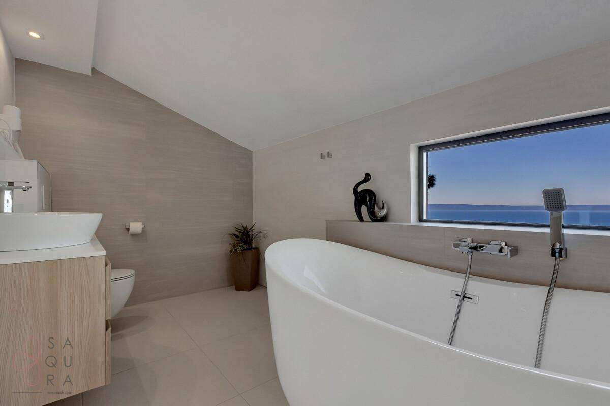 Modernes Badezimmer mit freistehender Badewanne, Waschtisch und Dachschräge, hell und geräumig.
