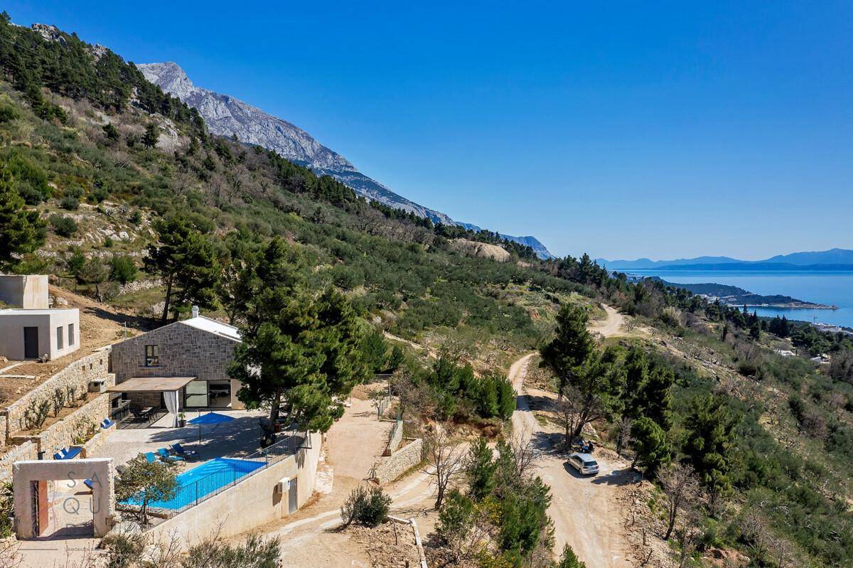 Weitläufige Luftaufnahme der Immobilie mit Pool, umgeben von grüner Landschaft und Meerblick.