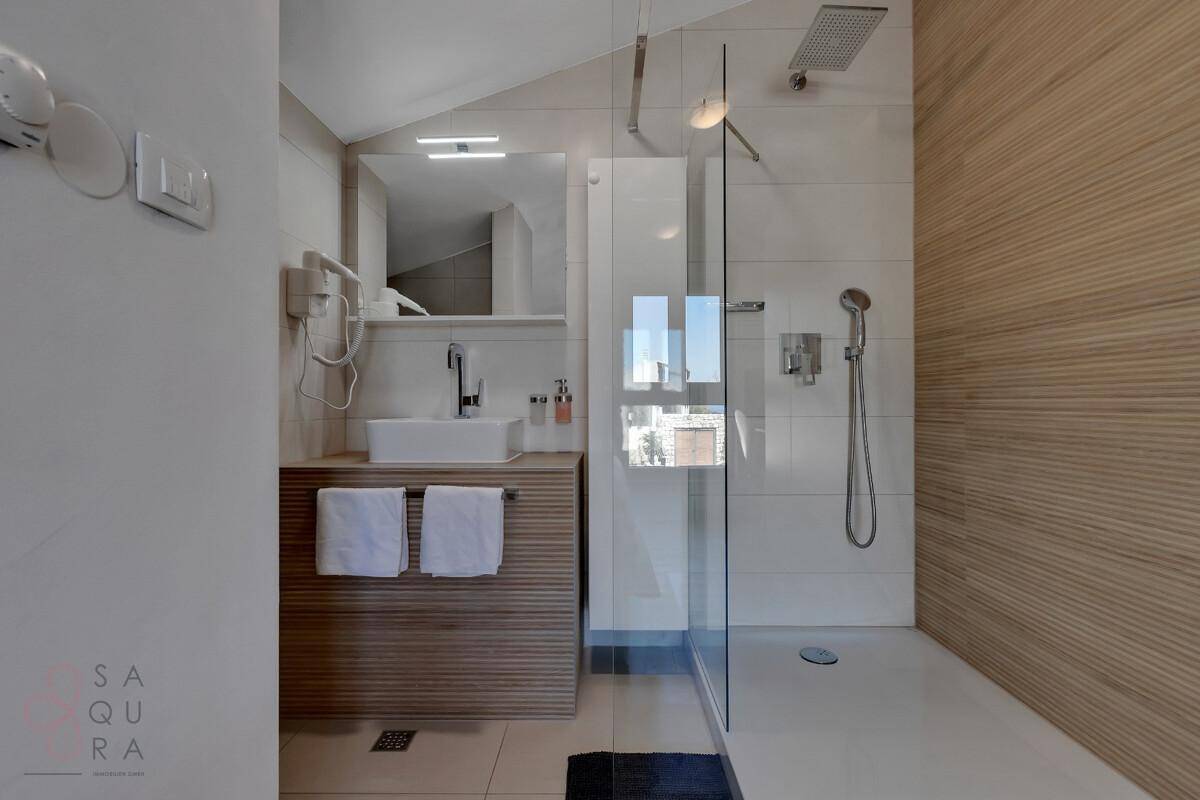 Modernes Badezimmer mit ebenerdiger Dusche, Waschtisch und Spiegel, hell und funktional.