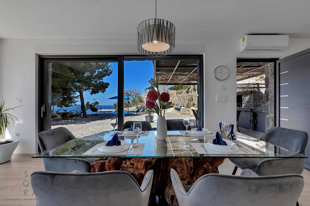 Eleganter Essbereich mit großem Tisch und Stühlen, direktem Zugang zur Terrasse und Meerblick.