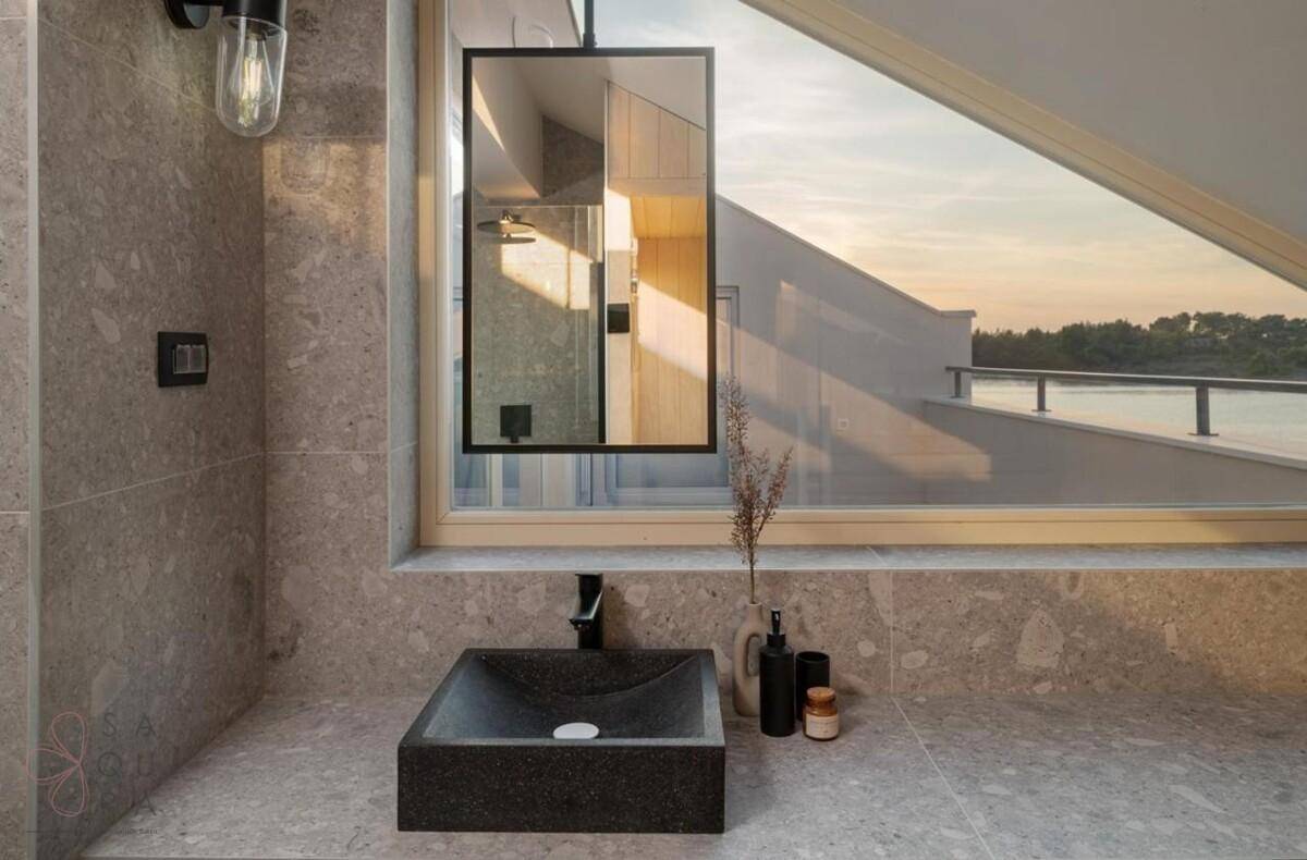 Modernes Badezimmer mit Steinfliesen, stilvollem Waschbecken und großem Fenster mit Ausblick.