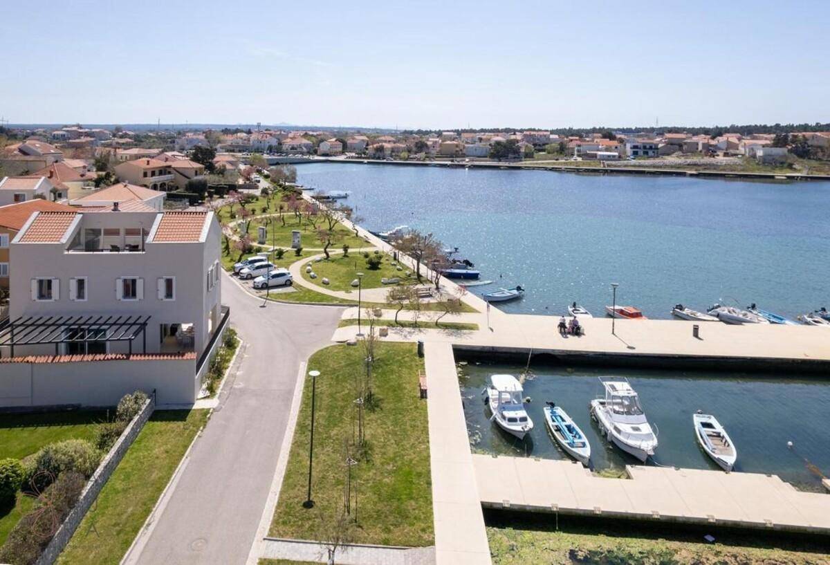 Weitläufige Luftaufnahme des Anwesens am Wasser mit Blick auf den Hafen und die Küstenlinie.