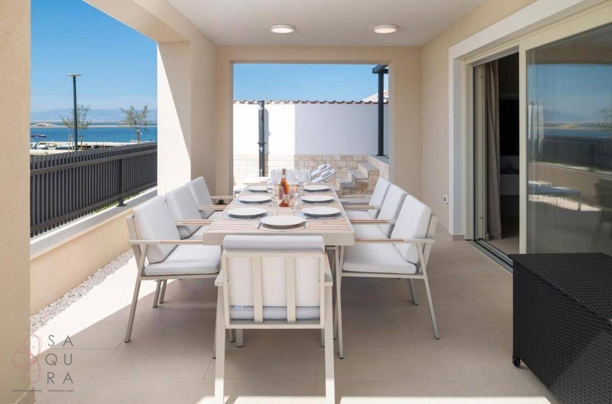 Geräumige überdachte Terrasse mit großem Esstisch und Zugang zum Innenbereich.