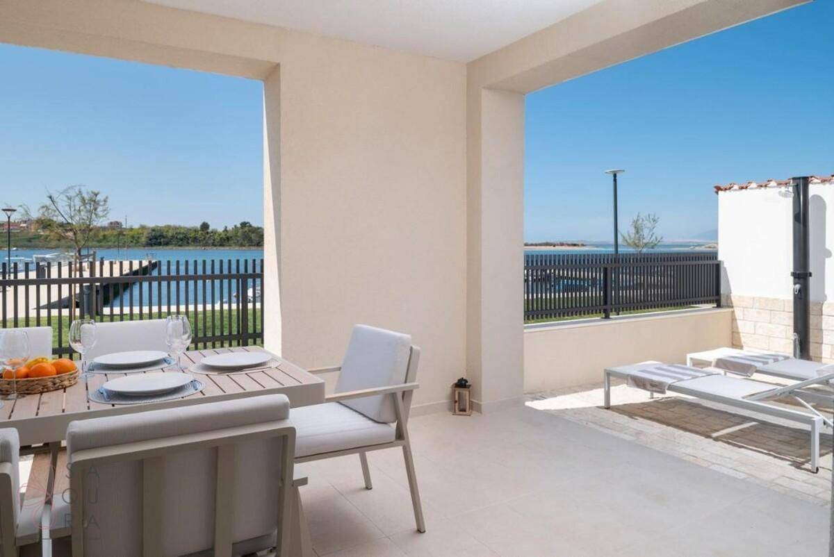 Große Terrasse mit Essbereich, Sonnenliegen und Außendusche, mit Blick auf das Wasser.