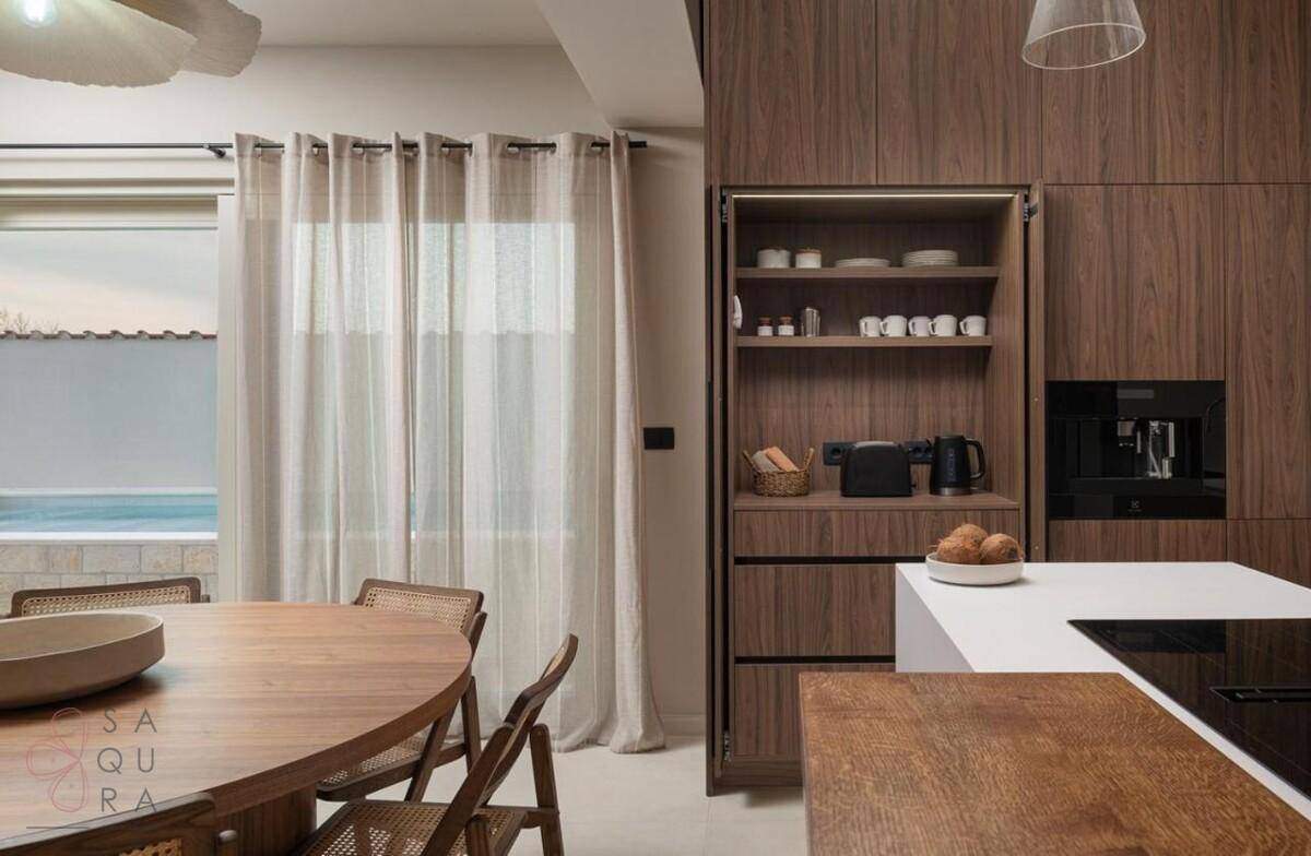 Detailansicht der modernen Küche mit integrierten Schränken, Speisekammer und Poolblick.
