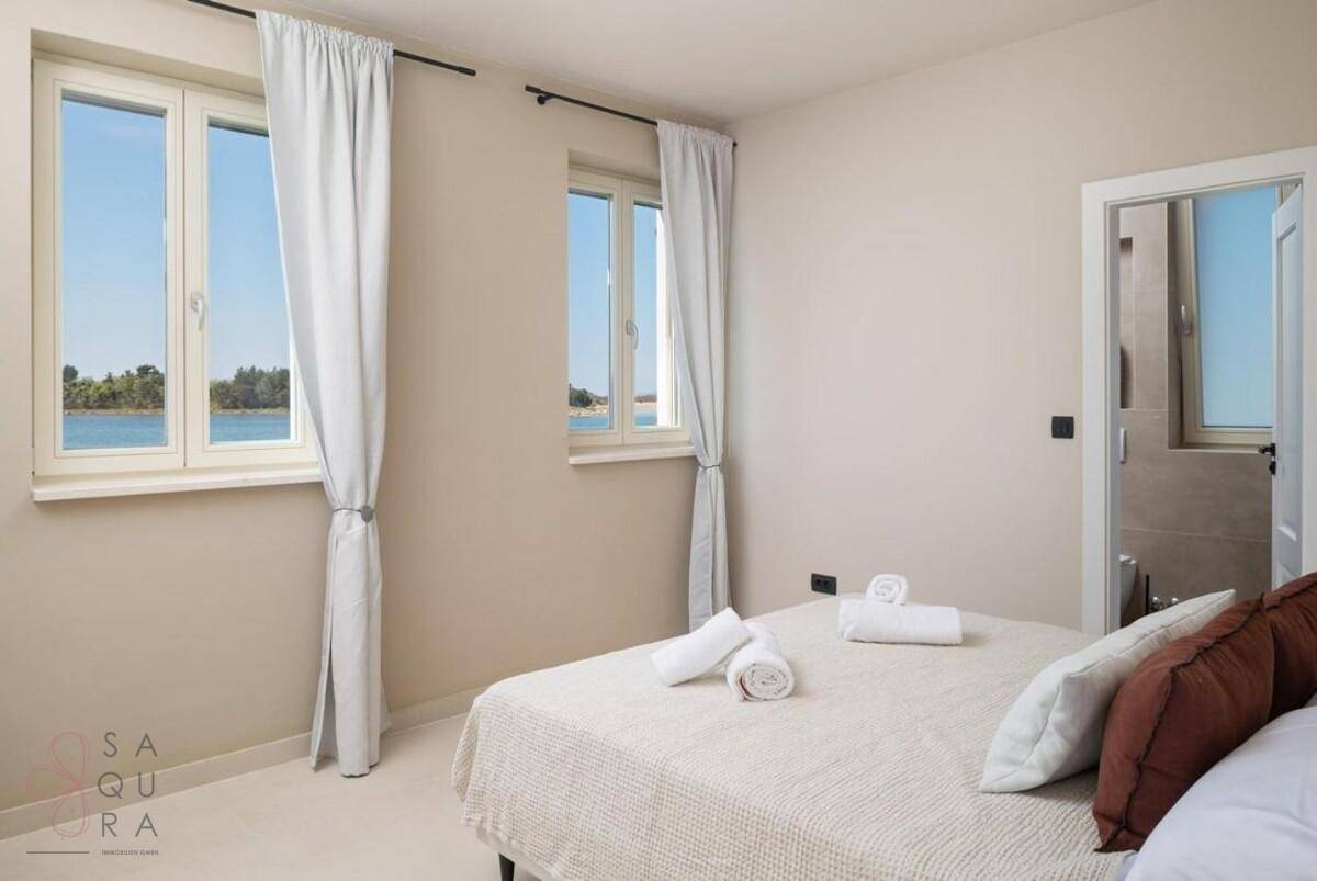 Helles Schlafzimmer mit Seeblick, bequemen Betten und direktem Zugang zu einem modernen Badezimmer.