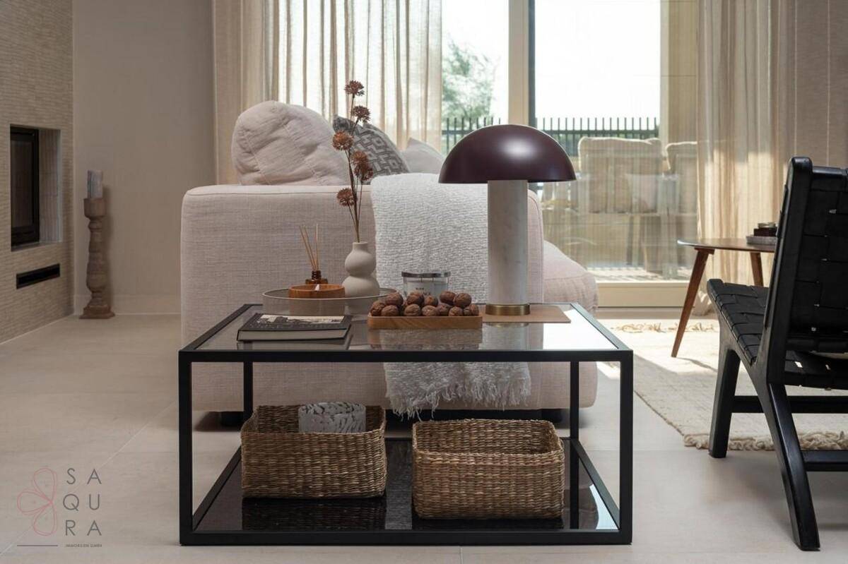 Moderner Couchtisch aus Glas und Metall im Wohnzimmer, mit Blick auf die Terrasse und bequemen Möbeln.