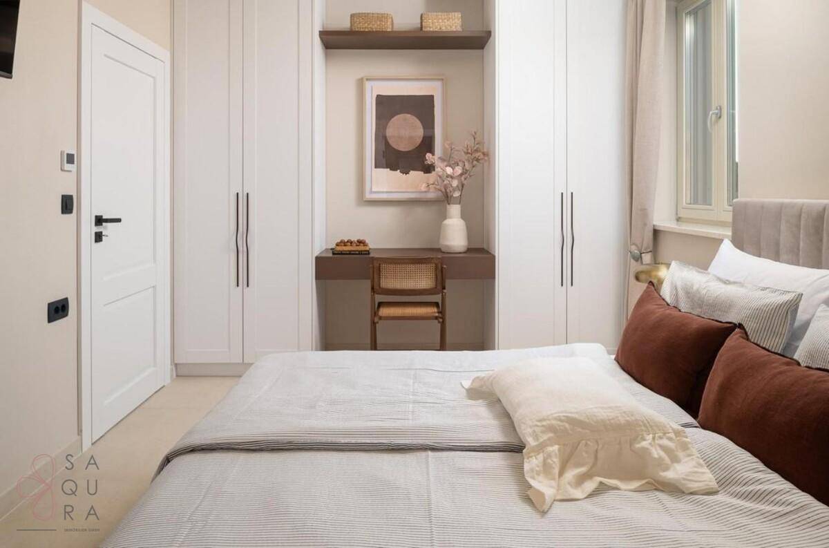Schlafzimmer mit großem Bett, integrierten Kleiderschränken und einem stilvollen Arbeitsbereich.