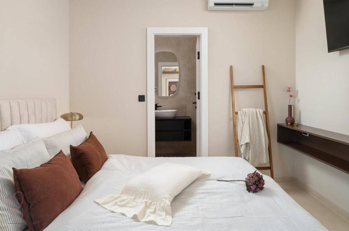 Gemütliches Schlafzimmer mit Doppelbett, Klimaanlage und direktem Zugang zu einem modernen Badezimmer.