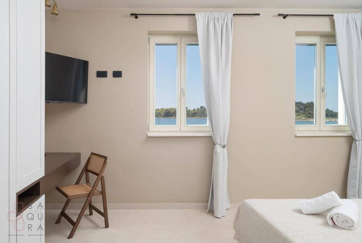 Schlafzimmer mit zwei Fenstern, die einen schönen Blick auf das Wasser bieten, und viel Tageslicht.