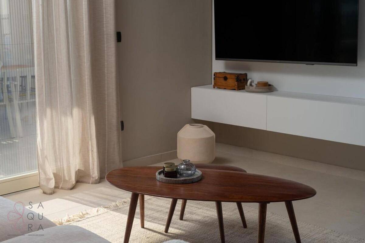 Eleganter ovaler Holztisch im Wohnzimmer, umgeben von moderner Einrichtung und viel Tageslicht.